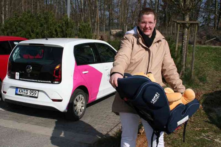 Frau mit Baby in Liegeschale - im Hintergrund Auto der Diakonie Sozialstation der Seniorenhilfe der Stiftung kreuznacher diakonie