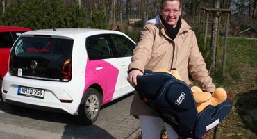 Frau mit Baby in Liegeschale - im Hintergrund Auto der Diakonie Sozialstation der Seniorenhilfe der Stiftung kreuznacher diakonie