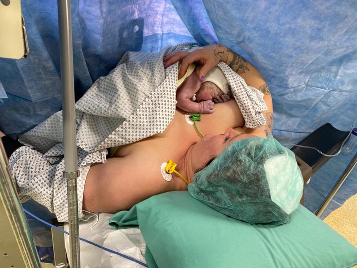 Neugeborenes liegt auf Brust der Mutter