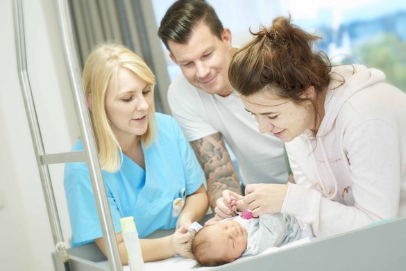 Neugeborenes mit Eltern und Pflegerin