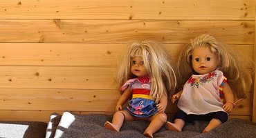 Zwei Puppen sitzen nebeneindaner. Symbol für Pflegeschwestern, Fachbertungsstelle Pflegefamilien Stiftung kreuznacher diakonie