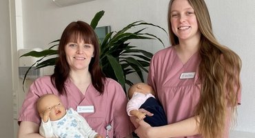 Zwei Hebammenstudentinnen der Hunsrück Klinik halten Babypuppen im Arm
