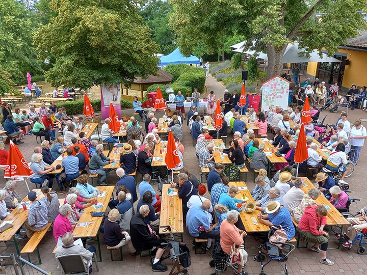Gäste sitzen an Biertischen im Freien beim Sommerfest auf dem Hüttenberg in Bad Sobernheim, Stiftung kreuznacher diakonie