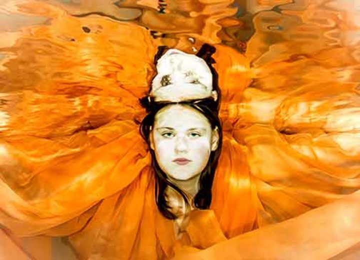Mädchen mit orangem Tuch unter Wasser