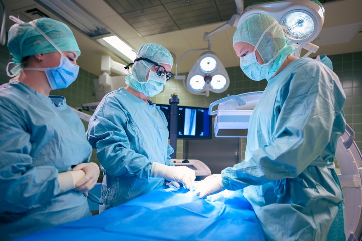 Eine Frau und zwei Männer operieren eine verstopfte Halsschlagader