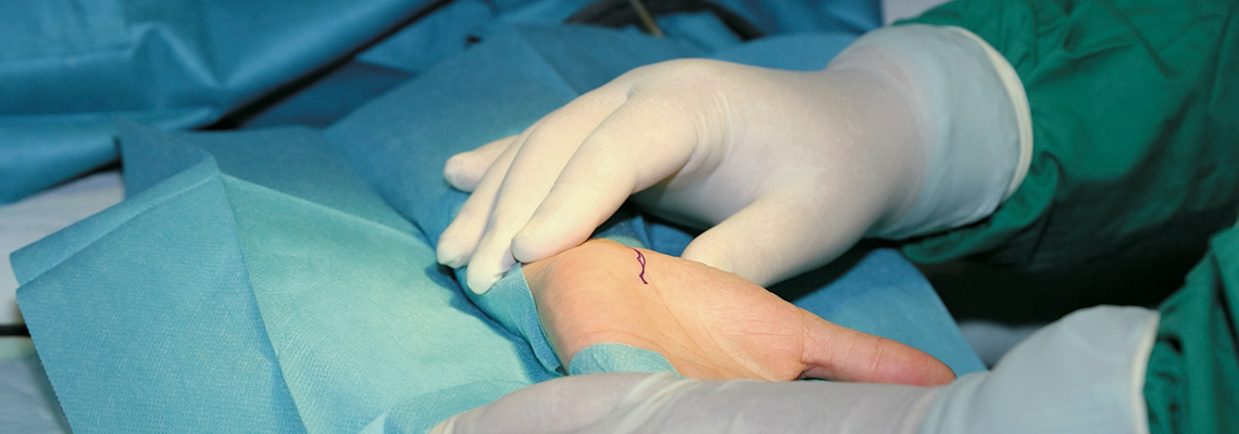 Chirurg untersucht Handgelenk eines Mannes